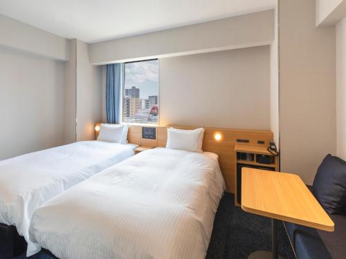 a hotel room with two beds and a window at Sotetsu Fresa Inn Sendai in Sendai