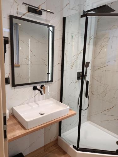 a bathroom with a white sink and a shower at Pokoje Gościnne u MARCINA- sala zabaw, basen, melex, rowery, grill in Ostrowo