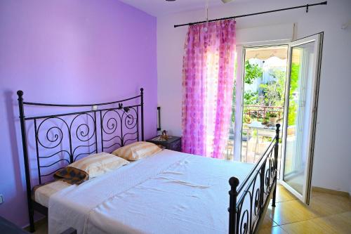 Schlafzimmer mit einem Bett mit rosa Wänden und einem Fenster in der Unterkunft D&M apartment in Polychrono