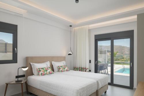 a white bedroom with a bed and a balcony at Exquisite Villas with Enchanting Surroundings, By ThinkVilla in Lambiní