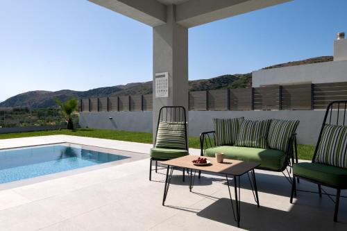 a patio with chairs and a table next to a swimming pool at Exquisite Villas with Enchanting Surroundings, By ThinkVilla in Lambiní