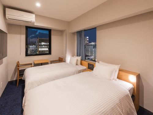 a hotel room with two beds and a window at Sotetsu Fresa Inn Sendai in Sendai