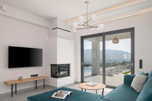 a living room with a blue couch and a tv at Exquisite Villas with Enchanting Surroundings, By ThinkVilla in Lambiní