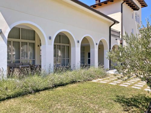 a white house with arched windows and grass at TOSCANINA Garni Hotel in Dobrovo