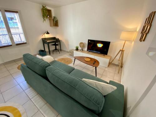 a living room with a green couch and a tv at Superbe appartement 2 pièces, plein centre ville. in Montlhéry