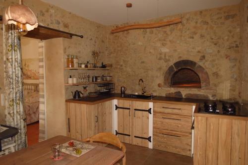 eine Küche mit Holzschränken und einer Steinwand in der Unterkunft Gîte écoconçu charmant proche zoo de la Flèche in Clermont-Créans