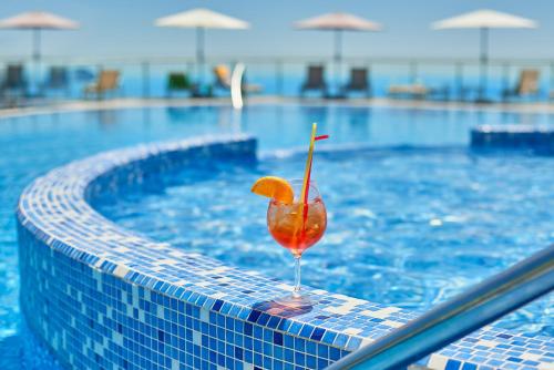 een drankje met een sinaasappelschijfje in een zwembad bij Villa Allende in Becici