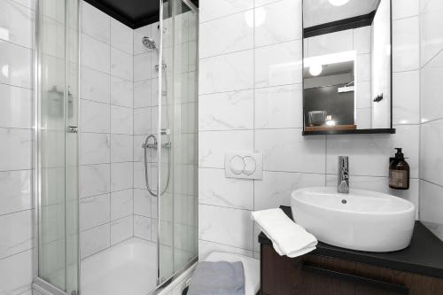 biała łazienka z umywalką i prysznicem w obiekcie Baldur Apartments w Reykjavík