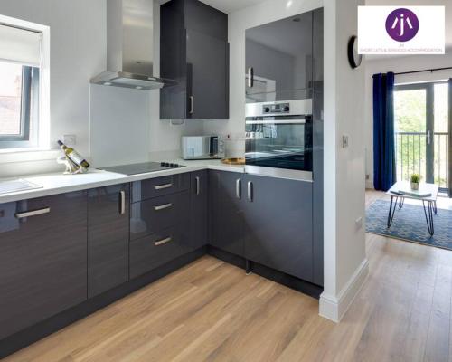 a kitchen with black and white appliances and wooden floors at Stevenage Luxury 1Bed Apartment - Sleeps 4-WIFI-Free Parking- By JM Short Lets & Serviced Accommodation in Stevenage