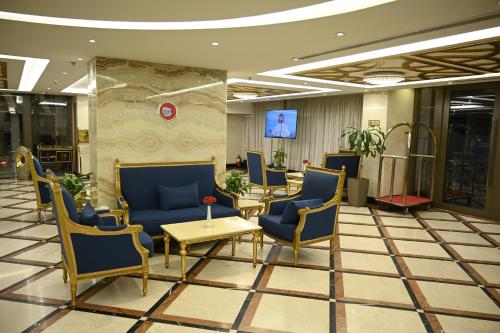 a lobby with chairs and tables and a tv at Aster Hotel in Jeddah