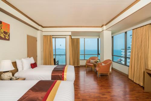 a hotel room with two beds and large windows at Cosy Beach Hotel - SHA Extra Plus in Pattaya South
