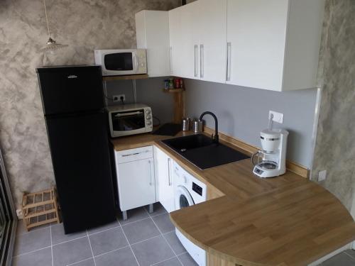 Il comprend une cuisine équipée d'un réfrigérateur noir et de placards blancs. dans l'établissement Studio avec splendide vue sur mer, au Lavandou