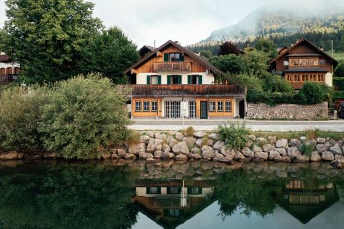 a house next to a body of water at Apartment am Grundlsee - Your Austrian Home in Grundlsee