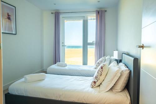 two beds in a room with a view of the beach at Luxury beach apartment in Perranporth