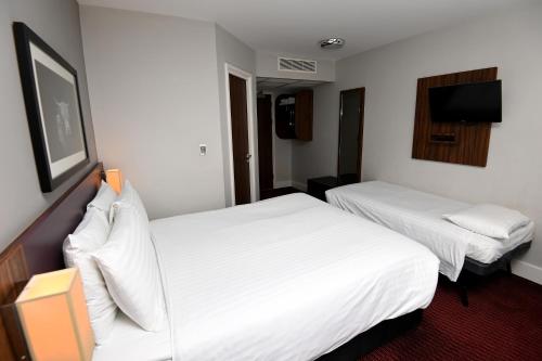 a hotel room with two beds and a flat screen tv at Pine Marten, Dunbar by Marston's Inns in Dunbar