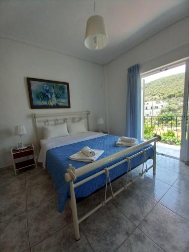 a bedroom with a bed with blue sheets and a window at Flisvos House in Megalochori