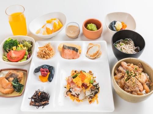 a white table with a plate of food and bowls of food at Sotetsu Fresa Inn Sendai in Sendai