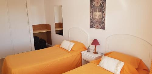 two beds in a small room with orange sheets at Lagoa Beach & Leisure in Costa de Santo André