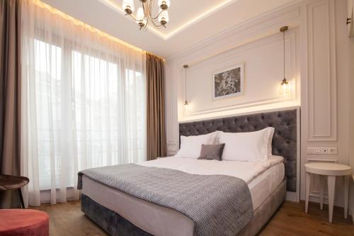 a bedroom with a large bed and a large window at Villa Flavia Heritage Boutique Hotel in Plovdiv