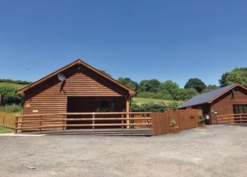 a log cabin with a fence in front of it at Heartsease Lodges in Llanddewi Ystradenny