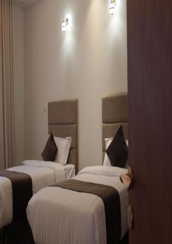- 2 lits dans une chambre d'hôtel de couleur blanche et brune dans l'établissement قوت المصيف للشقق الفندقية, à Hotat bani tamim