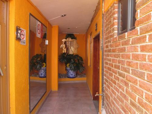 a hallway with yellow walls and a brick wall at Posada Arny in Tepotzotlán