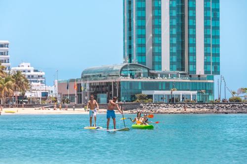 two men and a dog on paddle boards in the water at Arrecife Gran Hotel & Spa in Arrecife