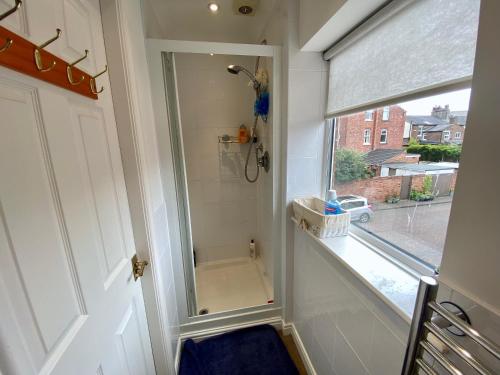 a bathroom with a shower with a mirror next to a window at Spacious Two Bedroom House - TM in Southport