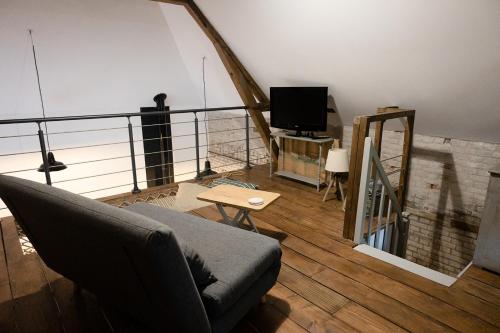 a living room with a couch and a tv at La maison au fil du temps in Pont-Rémy