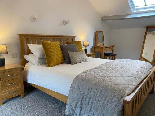 a bedroom with a large bed with yellow pillows at The Cottage on Fairbank - Kirkby Lonsdale in Kirkby Lonsdale