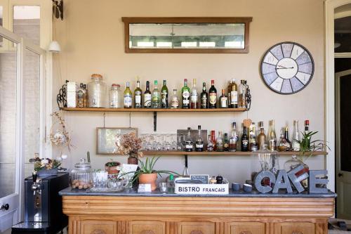 a bar with bottles and a clock on the wall at La maison au fil du temps in Pont-Rémy