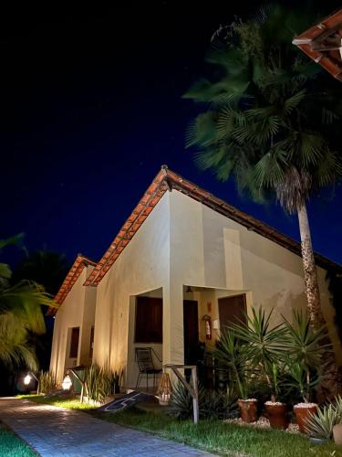 a white house with a palm tree at night at Pousada e Chalés Recantos do Mar in Barra Grande