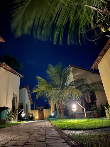 a night view of a house with a palm tree at Pousada e Chalés Recantos do Mar in Barra Grande