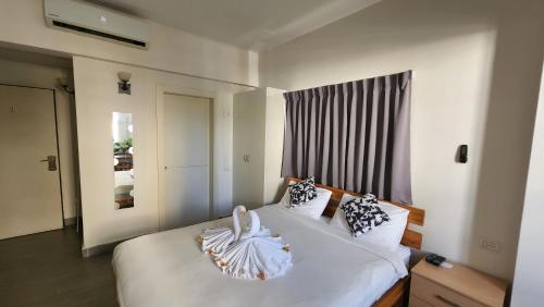 een slaapkamer met een bed met witte lakens en een raam bij David Hameleh House in Netanya