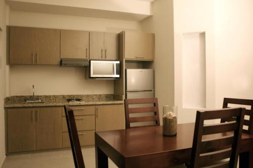 Una cocina con una mesa de madera y una mesa y sillas. en MARENA Suites & Apartments, en Mazatlán