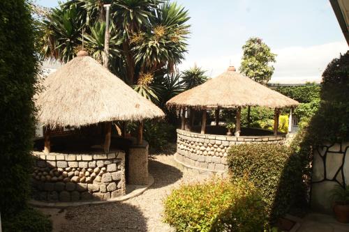 dos cenadores en un jardín con palmeras en La paillotte gorilla place kinigi, en Kinigi