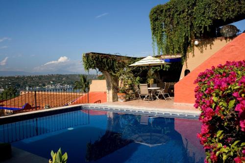a swimming pool with a table and chairs and flowers at La Casa del Guamúchil in Tequesquitengo