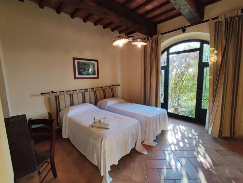 a bedroom with two beds and a large window at Agriturismo Santa Cristina in Gambassi Terme