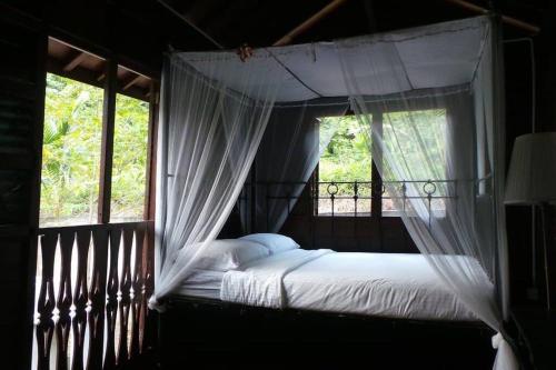 a bedroom with a canopy bed with a window at THE DENAI Langkawi in Kuah