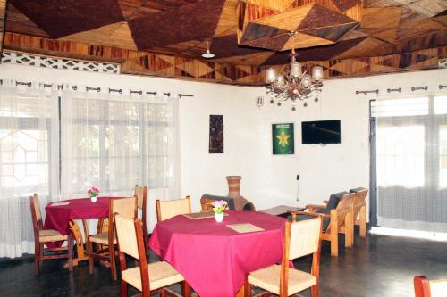 una sala da pranzo con tavoli, sedie e lampadario a braccio di La paillotte gorilla place kinigi a Kinigi