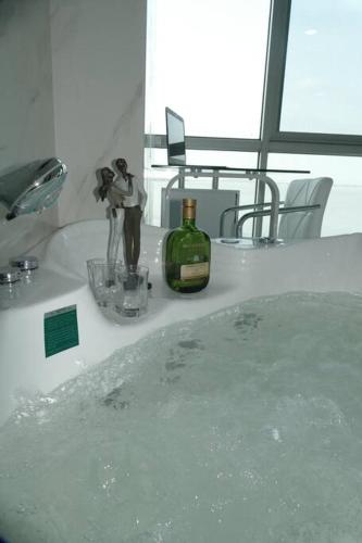 a bathroom with a sink with a bottle of wine at Ecusuites Studio Two Riverfront con Jacuzzi Hidro Privado in Guayaquil