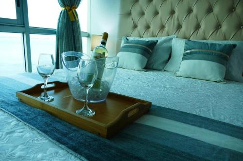 a tray with two glasses and a bottle of wine on a bed at Ecusuites Studio Two Riverfront con Jacuzzi Hidro Privado in Guayaquil