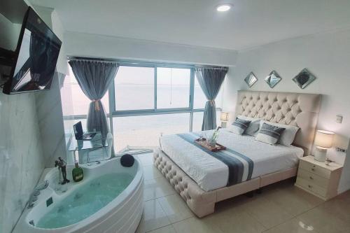 a bedroom with a bed and a tub and a window at Ecusuites Studio Two Riverfront con Jacuzzi Hidro Privado in Guayaquil