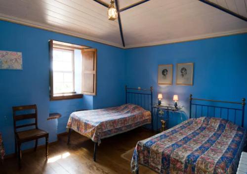 1 dormitorio azul con 2 camas y 1 silla en SOLAR DAS ARCAS Manor House - Deluxe Mountain AP, en Arcas