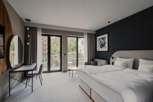 a bedroom with a large white bed and a desk at BELMONTE Hotel Krynica-Zdrój in Krynica Zdrój