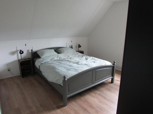 een slaapkamer met een bed met witte lakens en kussens bij De Steerne, mooie plek aan het Overijssels kanaal. in Schalkhaar