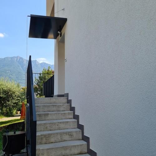 eine Treppe, die zu einem weißen Gebäude mit einer Flagge führt in der Unterkunft Appartamento Ticino in Monte Carasso