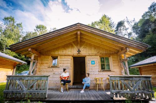 two people sitting on the porch of a log cabin at AREA 47 - Tirol in Ötztal-Bahnhof