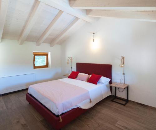 a bedroom with a large bed with red pillows at Tenuta Della Casa Wine & Rooms - La Pausa del Collio in Cormòns