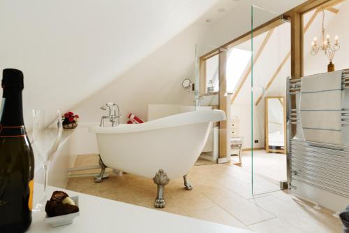 a white bath tub in a bathroom with a staircase at Honeysuckle Cottage in Thornham Magna